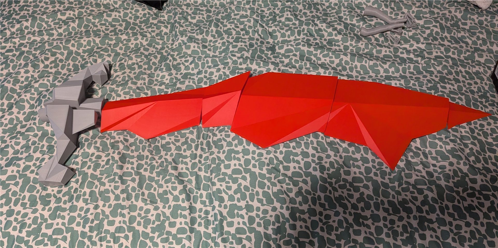 Life-sized Old School RuneScape dragon scimitar cosplay prop assembled on a bed
