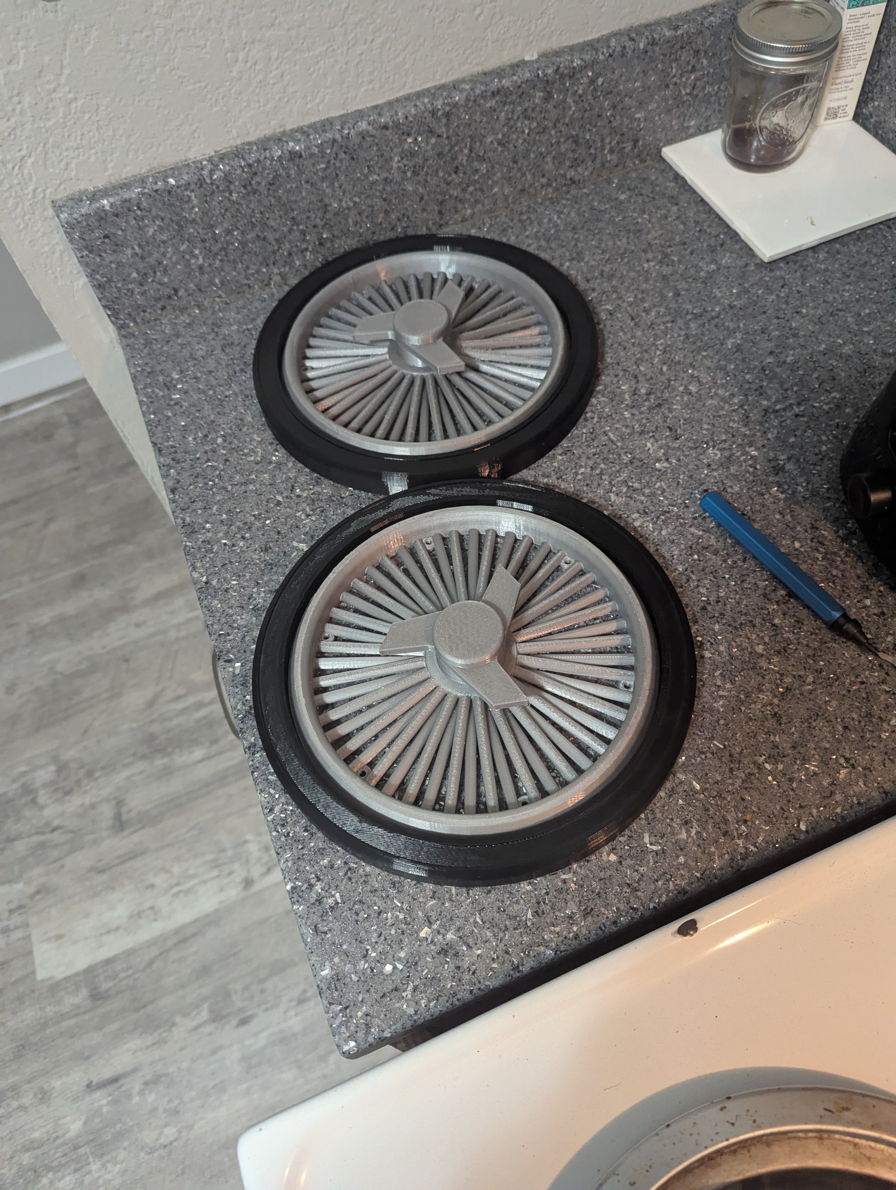 Finished trash can wheel covers with black outer rings and gray spoke centers
